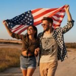 Man wearing Frontier Rogue True Feeling Can't Be Bought Can't Be Faked graphic tee with woman and Amerian flag in outdoor setting