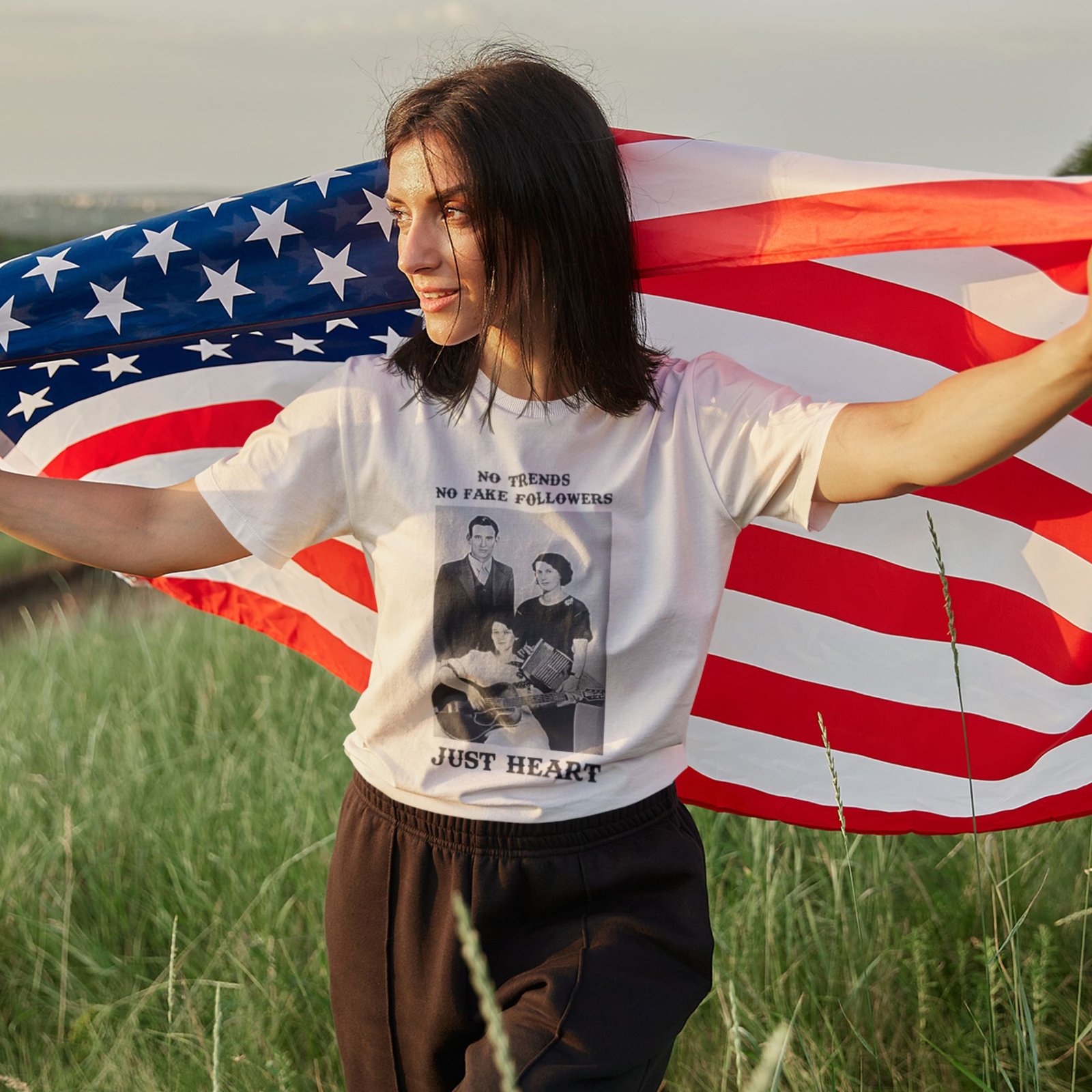 Woman wearing Frontier Rogue No Trends No Fake Followers Just Heart graphic tee with American flag in outdoor setting