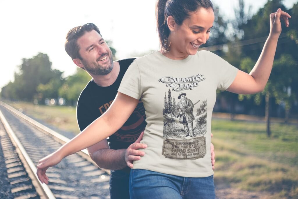 Woman wearing Frontier Rogue Calamity Jane shirt on train tracks with man