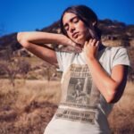 Woman wearing Frontier Rogue Belle Starr Wanted Poster graphic tee in outdoor desert setting