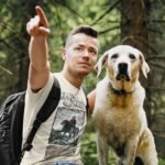 Man wearing Frontier Rogue Kit Carson graphic tee in outdoor setting with dog
