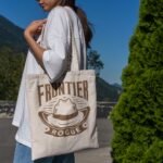Woman holding Frontier Rogue Logo Tote Bag in nature